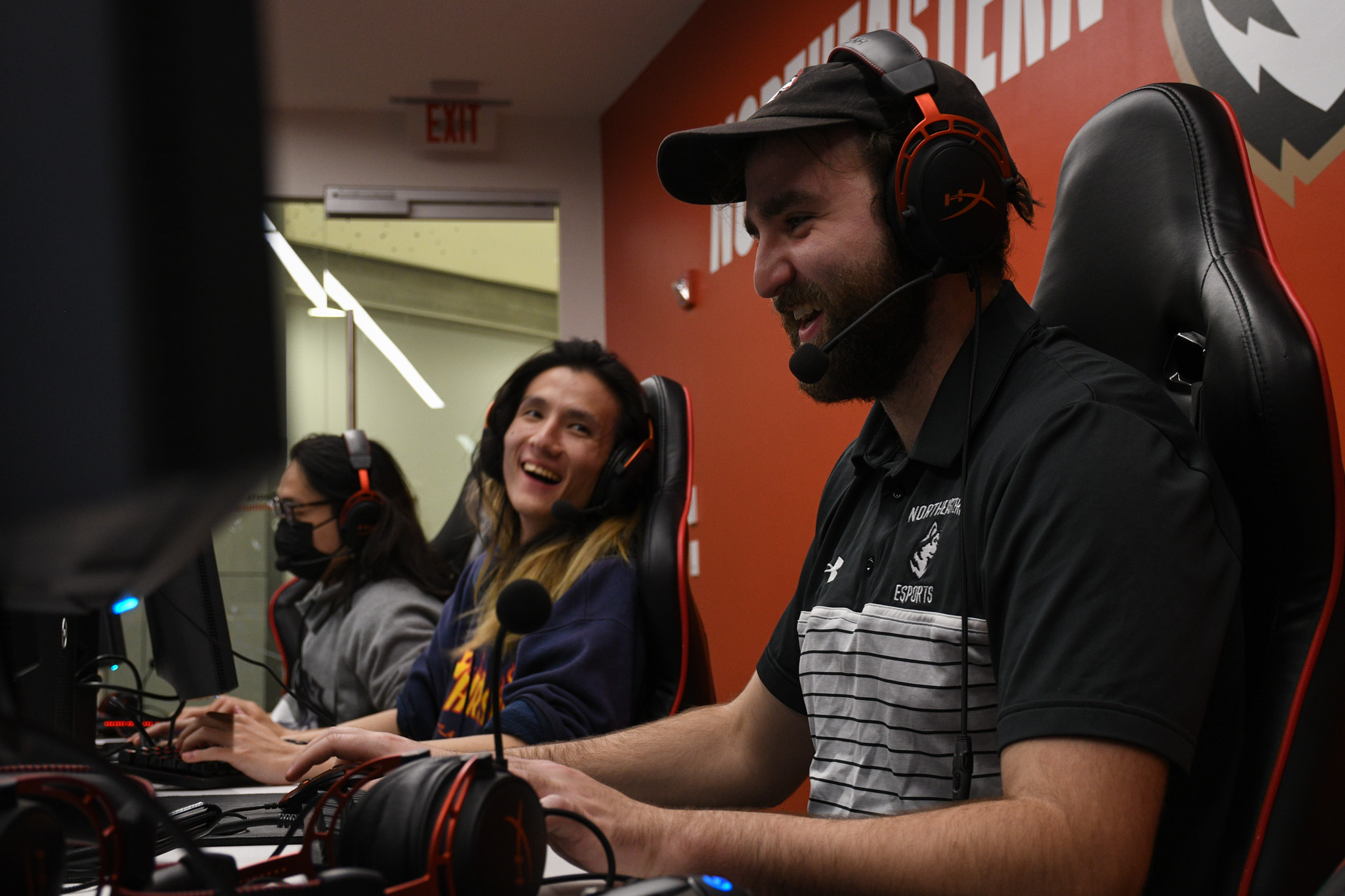 Two young men playing video games grin at each other.