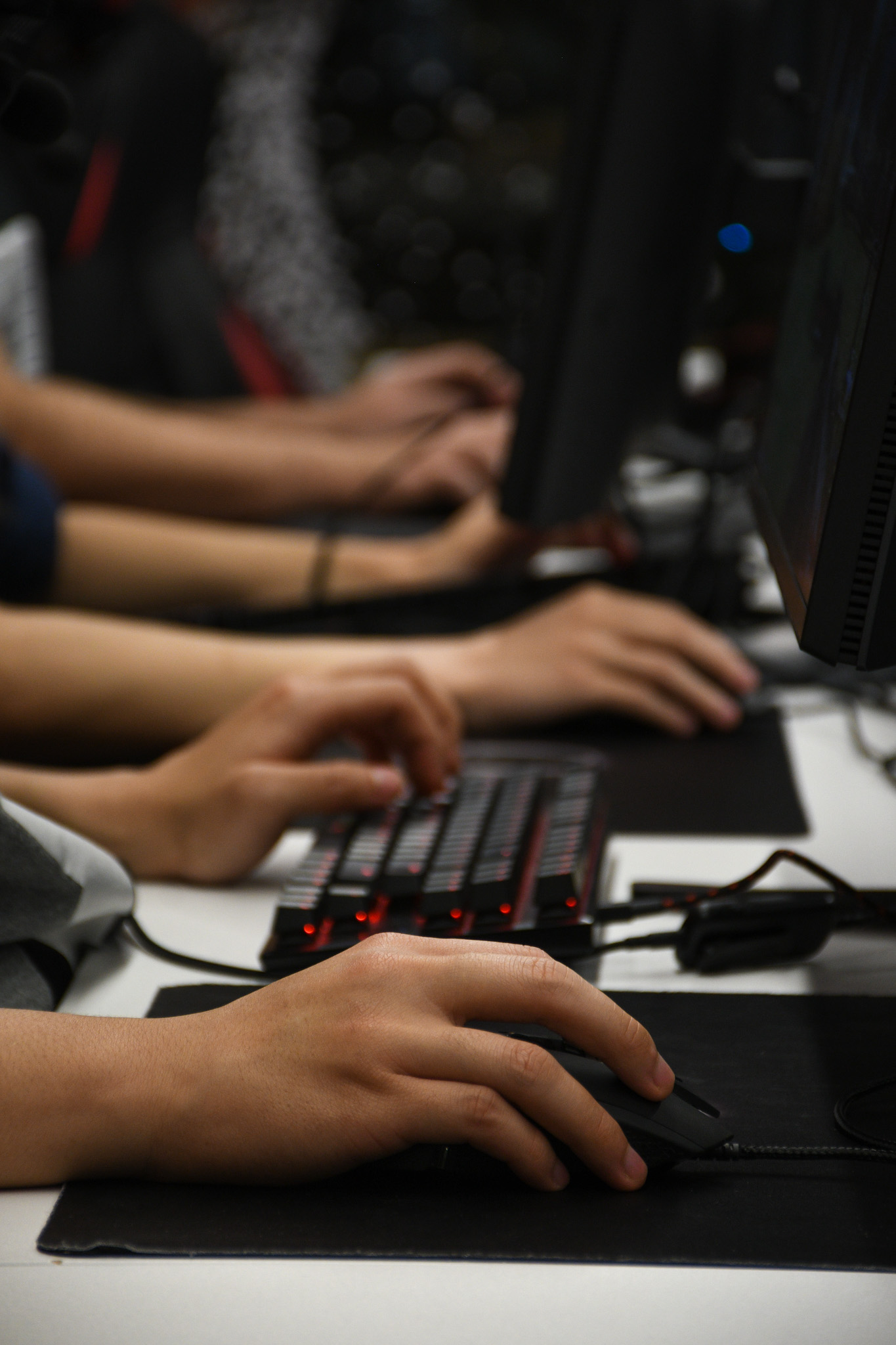 Three pairs of hands interact with mice and keyboards.